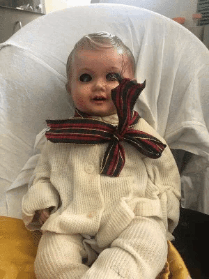 a doll with a scarf around its neck is sitting on a chair