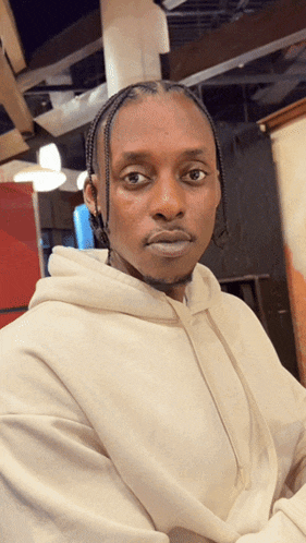 a man in a white hoodie looks at the camera with a serious look on his face