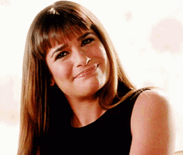 a woman with long hair and bangs is smiling and wearing a black top