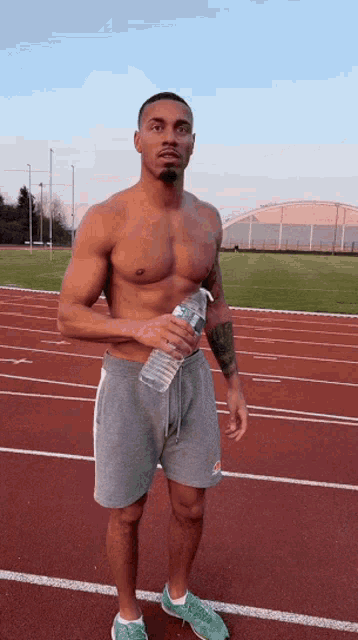 a shirtless man is holding a bottle of water