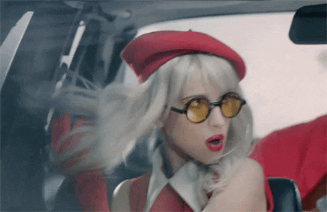 a blonde woman wearing a red beret and sunglasses is sitting in a car .