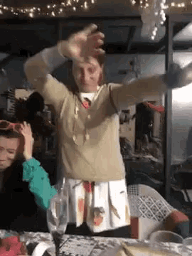 a woman in a tan sweater is dancing in a room