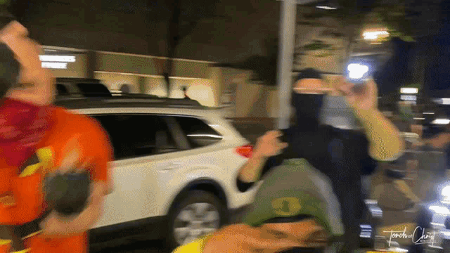 a blurry photo of a group of people with a white suv in the background and the name jonathan craig written on the bottom