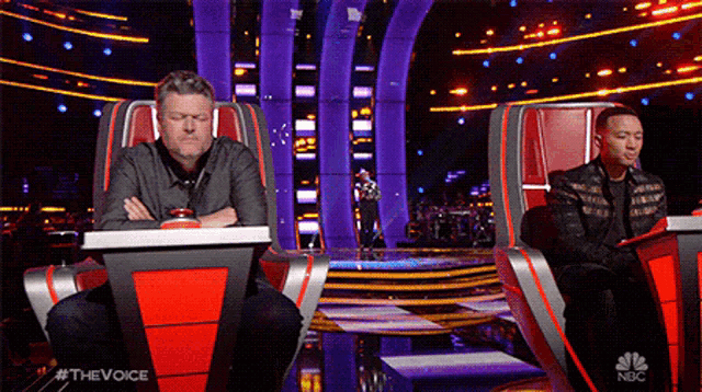 two men are sitting in front of a stage with a nbc logo on the bottom right