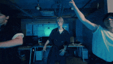 a group of young men are dancing in a dark room and one of them is wearing a sweater with the letter d on it