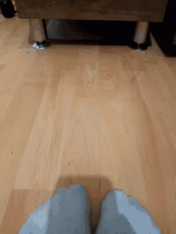 a person 's feet are standing on a hardwood floor