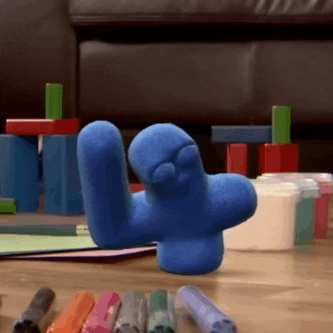 a blue toy is laying on a wooden floor next to crayons and blocks .