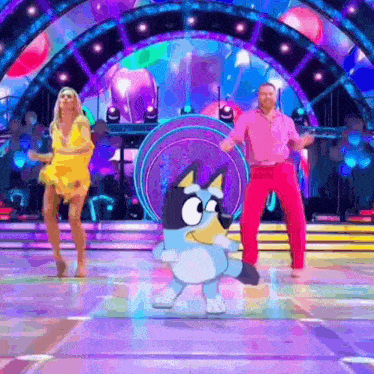 a man and a woman are dancing on a stage with a cartoon dog .