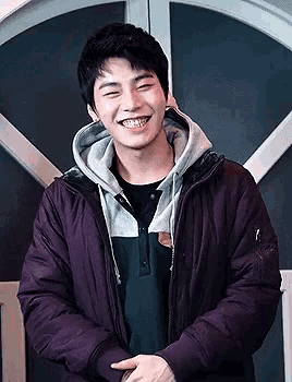 a young man wearing a purple jacket and a hooded sweatshirt is smiling .