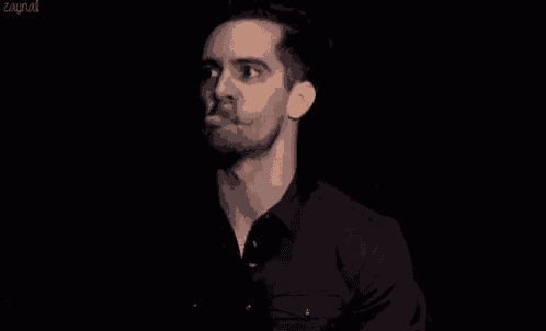 a man in a black shirt is smiling with his eyes closed and his mouth open .