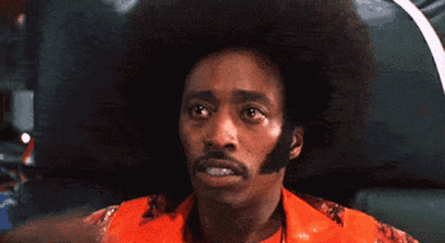 a man with an afro and a beard is wearing a red shirt
