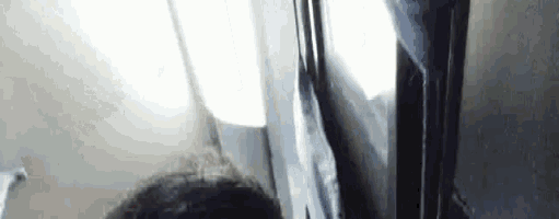a man is sitting on an airplane looking out of the window .