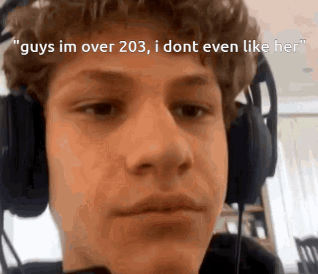 a young man wearing headphones with the words " guys im over 203 i dont even like her "