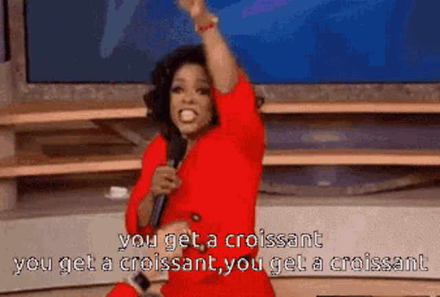 a woman in a red dress holds a microphone and says you get a croissant