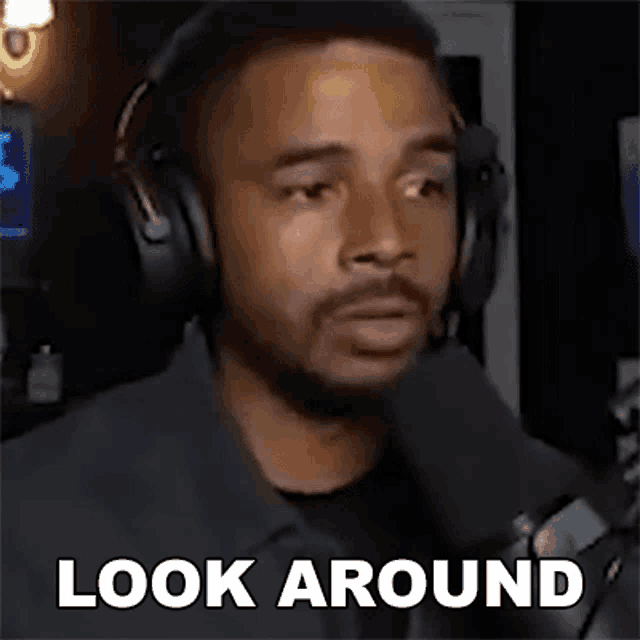 a man wearing headphones and a microphone is talking into a microphone and saying `` look around '' .