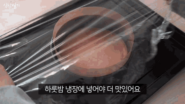 a person is wrapping a cake in plastic wrap with korean writing on the bottom