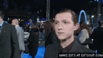 a man in a suit and tie is standing in front of a crowd .