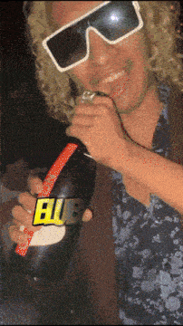 a man wearing sunglasses and a wig is holding a bottle of bubble
