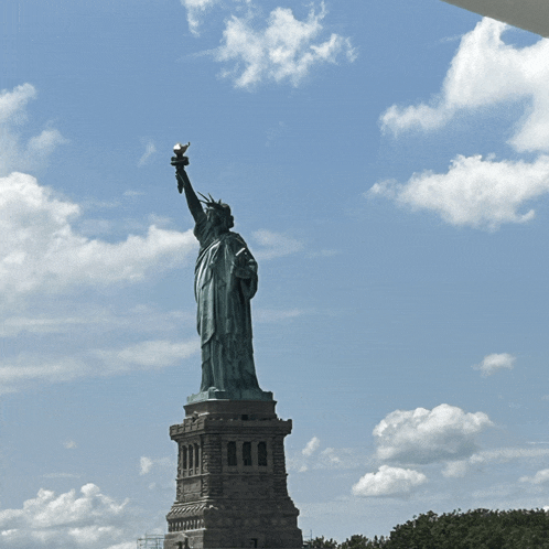 the statue of liberty stands tall against a cloudy sky