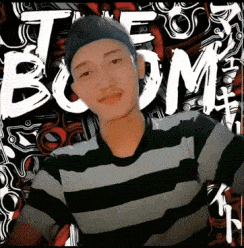 a man wearing a hat and striped shirt stands in front of a poster that says boom