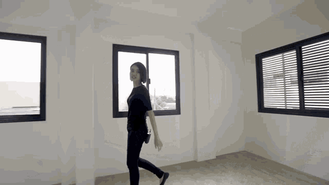a woman is walking through an empty room with lots of windows