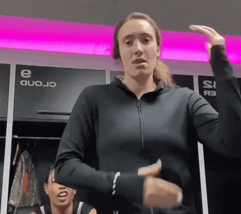 a woman in a black jacket stands in a locker room with a sign that says ' crond ' on it