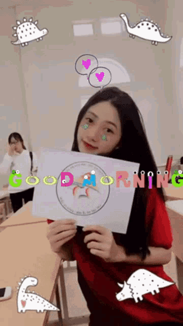 a girl in a red shirt is holding up a piece of paper that says good morning