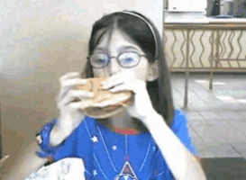 a girl with glasses is eating a hamburger