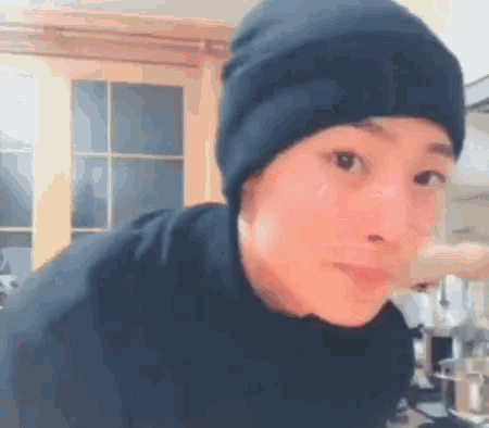 a person wearing a black beanie and a black shirt is making a funny face
