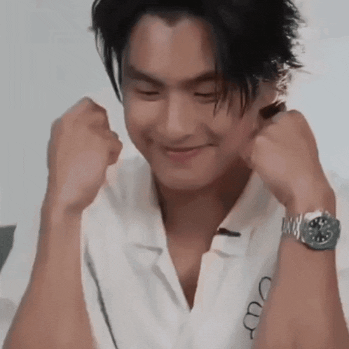 a man wearing a white shirt and a watch is smiling and making a funny face .