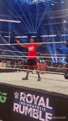 a man in a red shirt is standing in a wrestling ring at the royal rumble in indianapolis