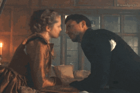a man and woman are kissing in a room with a candle .