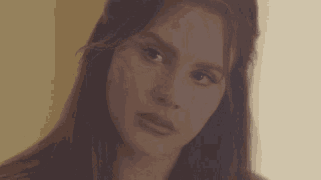 a close up of a woman 's face with long hair and a serious look on her face .