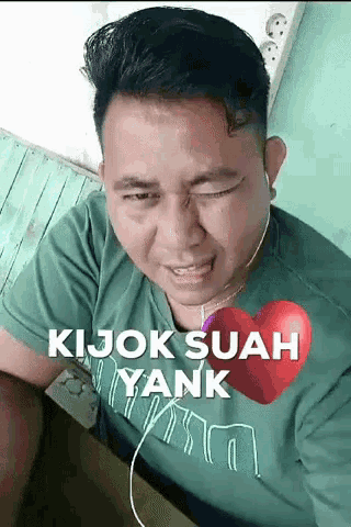 a man wearing a green shirt with a heart on it
