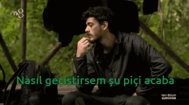 a man in a black jacket sits in front of a tv screen that says survivor on it