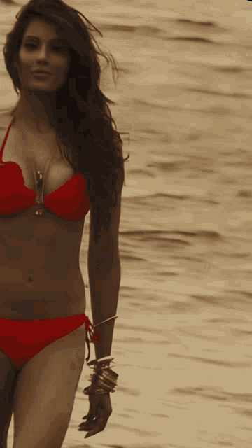 a woman in a red bikini is walking along the beach