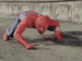a close up of a person in a spiderman costume doing a handstand on the ground .