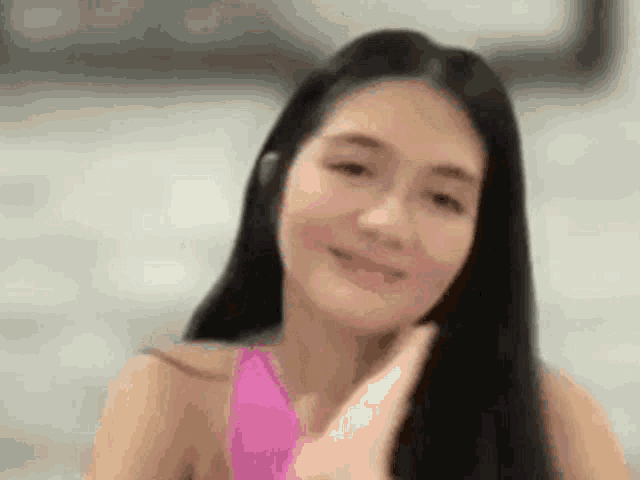 a woman with long black hair is wearing a pink bikini and smiling .