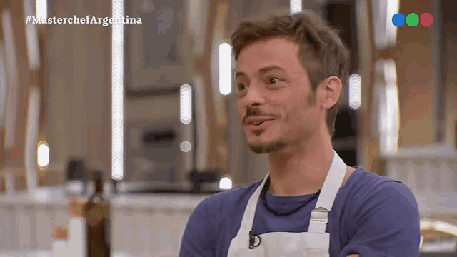 a man in a blue shirt and white apron is on a television show called masterchef argentina