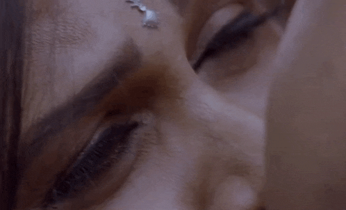 a close up of a woman 's face with her eyes closed and a necklace on her forehead .