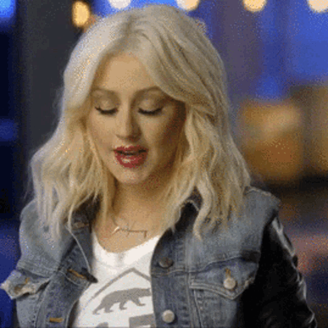 a blonde woman wearing a denim jacket and a t-shirt with a bear on it