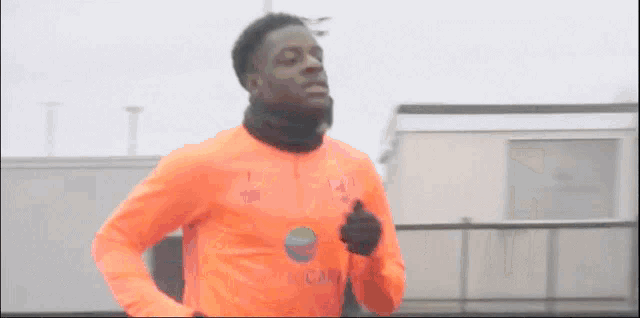 a man wearing an orange shirt that says ' aa ' on it is running