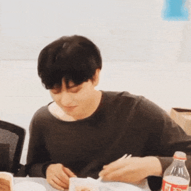a man is sitting at a table with a bottle of coca cola in front of him