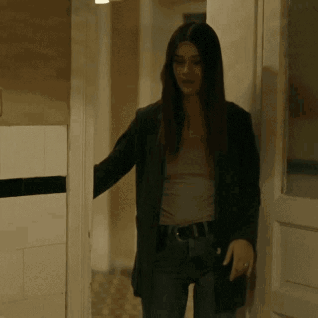 a woman is standing in a hallway wearing a black jacket