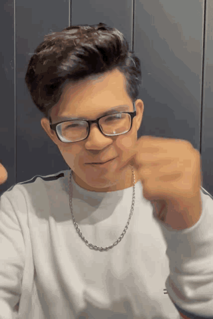 a man wearing glasses and a white shirt is giving a thumbs up