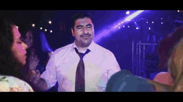 a man in a white shirt and tie is dancing in a crowd