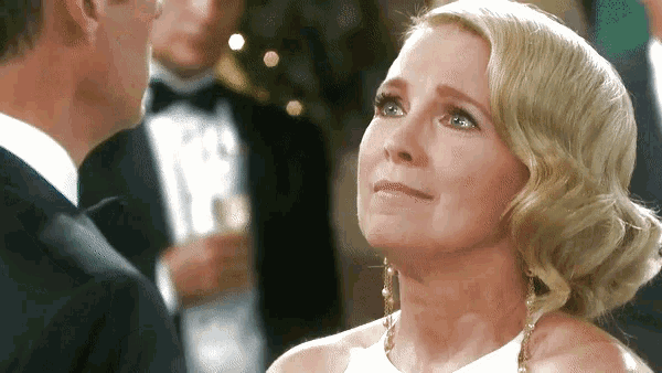 a woman in a white dress is crying while looking up at a man in a tuxedo