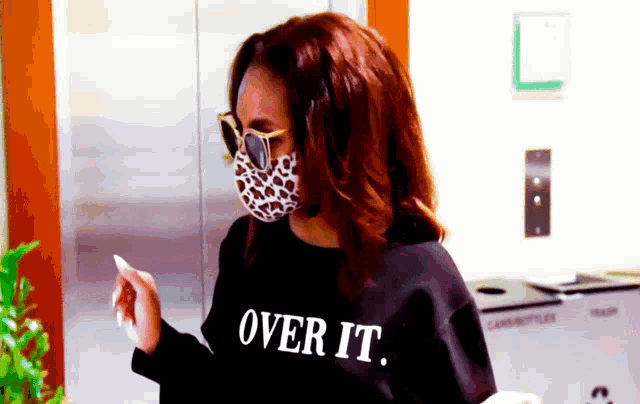 a woman wearing a face mask and a sweatshirt that says over it .