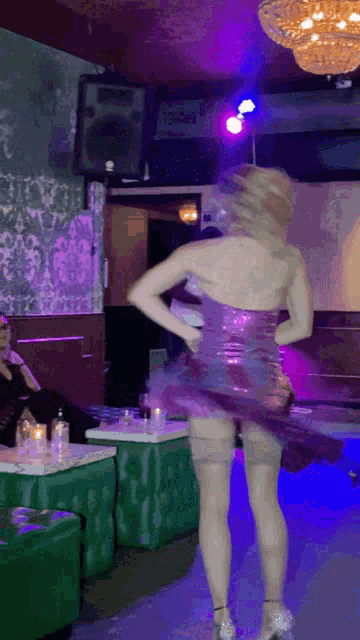 a woman in a purple dress is dancing in a dark room
