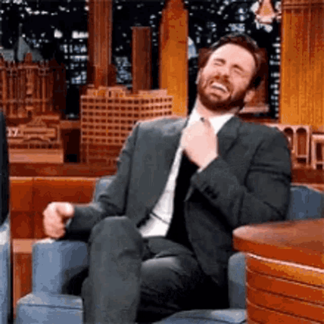 a man in a suit is sitting in a chair and smiling .
